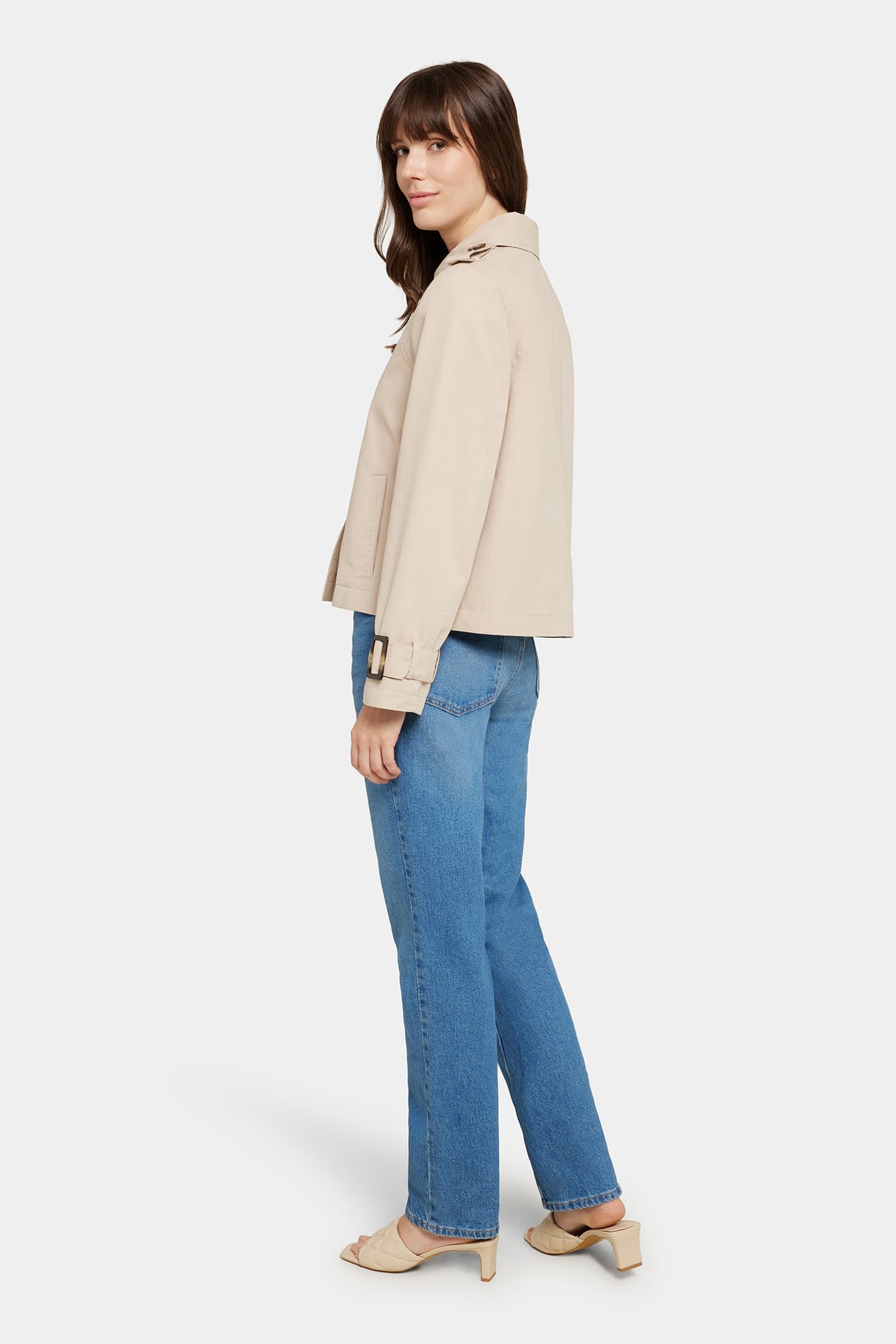 Side view of the Serafina jacket in classic beige, highlighting the cropped silhouette, structured collar, and belted cuffs.