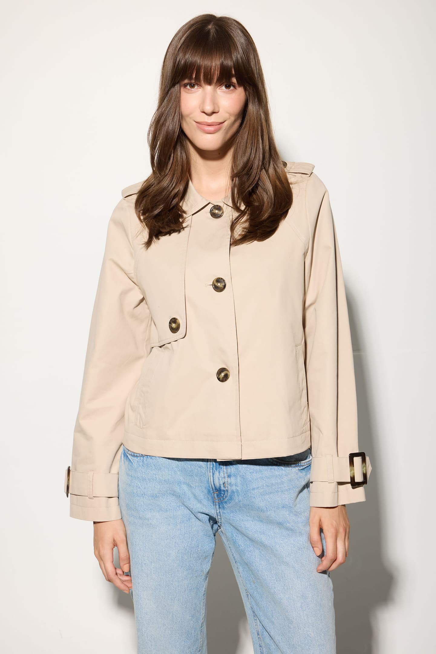Model wearing the Serafina jacket in classic beige, front view with arms relaxed and jacket buttoned up.