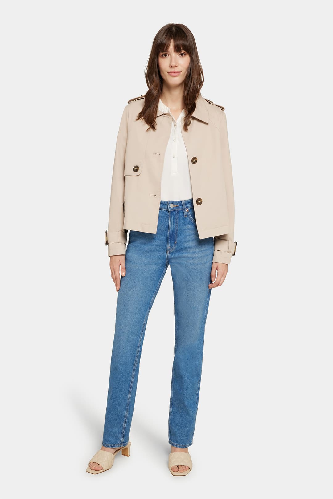Model wearing the Serafina jacket in classic beige, front view with the jacket open over a white top and blue jeans.